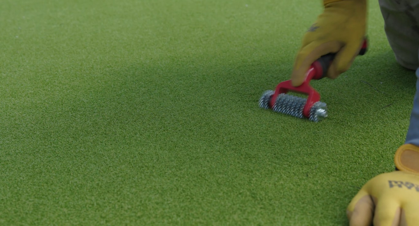 Professional maintaining high-quality playground turf with specialized tools in Chico, CA